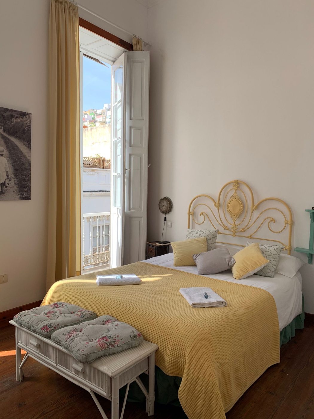 Letto con coperta gialla in una camera luminosa