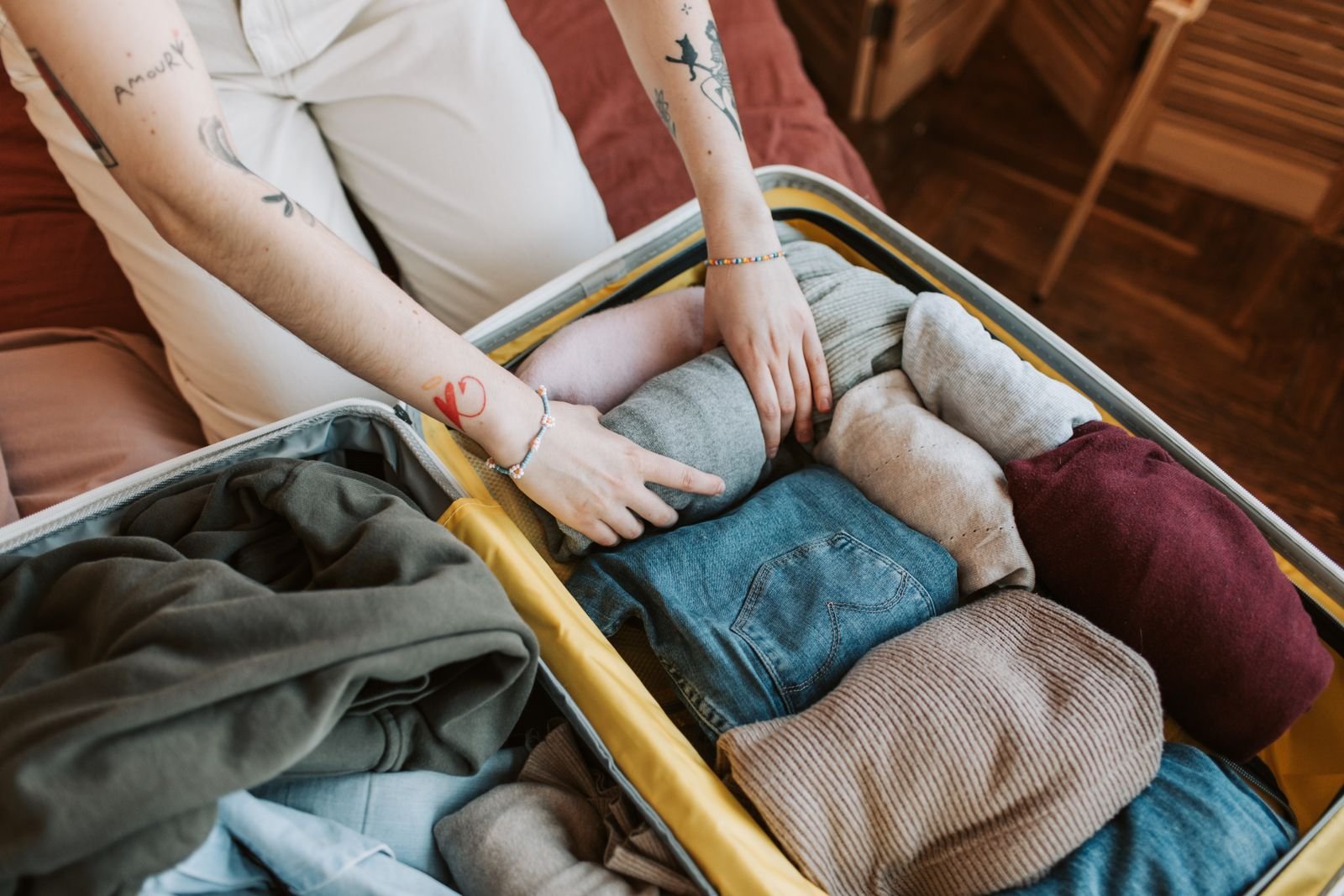 Mani che sistemano vestiti arrotolati in una valigia