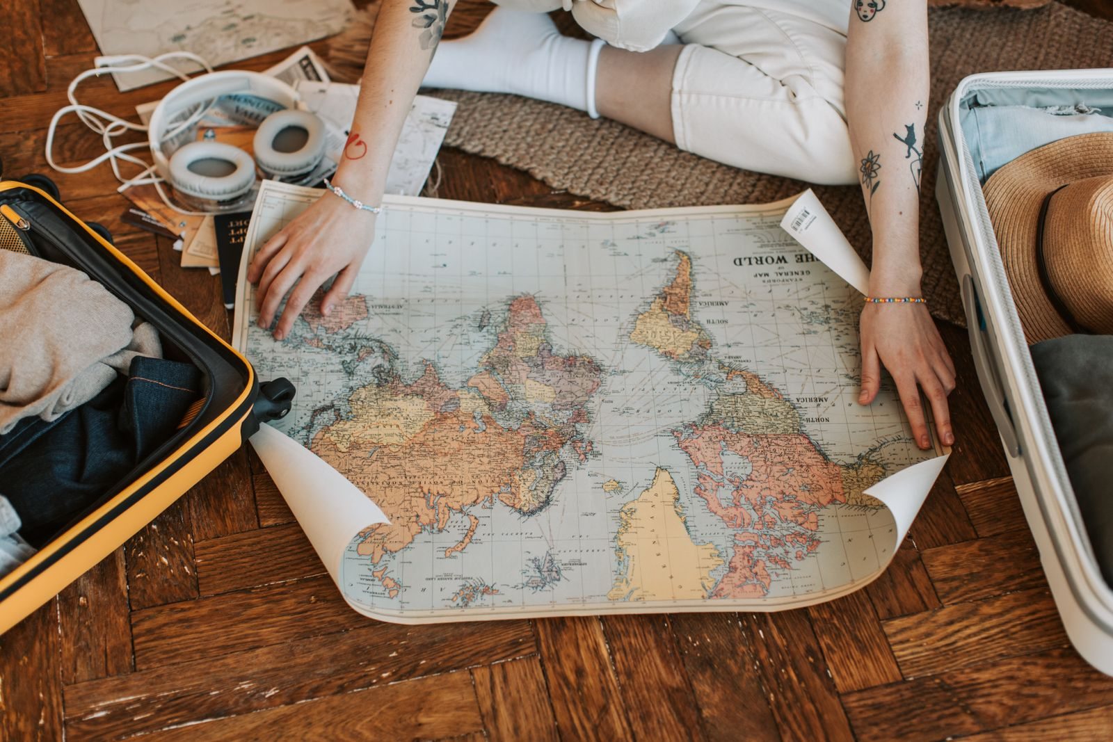 Mani che aprono una mappa accanto a una valigia